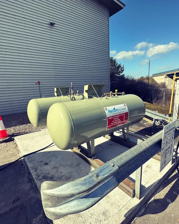 Above-ground LPG tanks behind a steel safety barrier at an industrial building