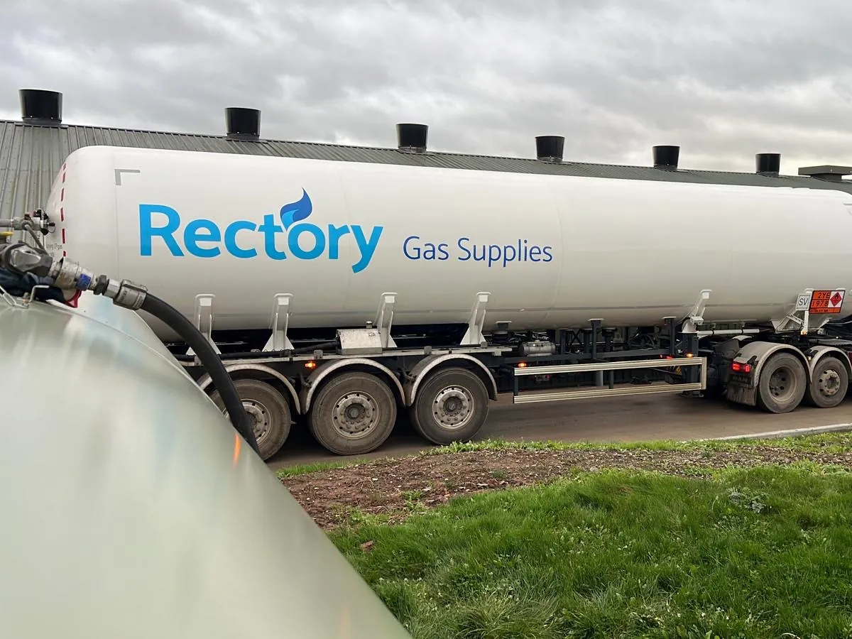 A Rectory Gas Supplies articulated LPG tanker delivering to a tank beside a long green farm building