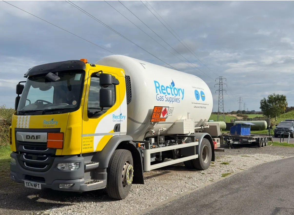 A Rectory Gas Supplies LPG tanker parked on a gravel drive beside a country road under a cloudy sky